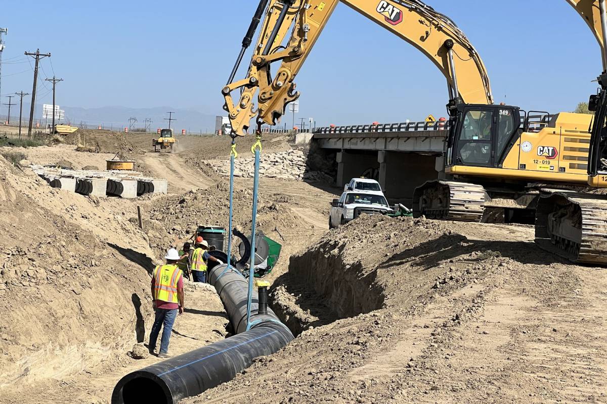 heavy equipment and workers install a pipeline