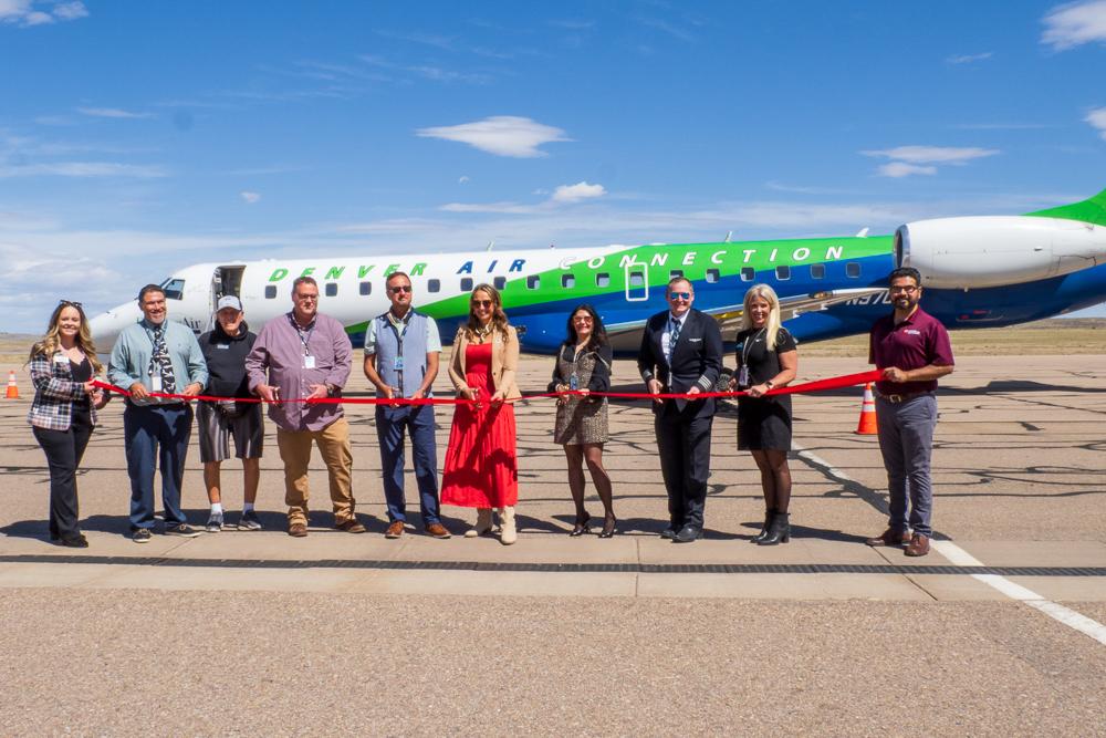 People cut a red ribbon with a jet in the background